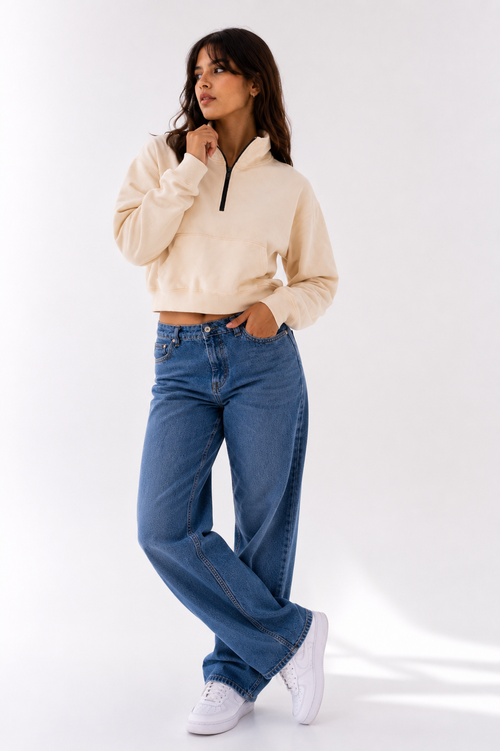 Female model wearing the Beige Crop Zipper with light blue wide-leg denim, showcasing the relaxed cropped fit and premium neutral aesthetic.
