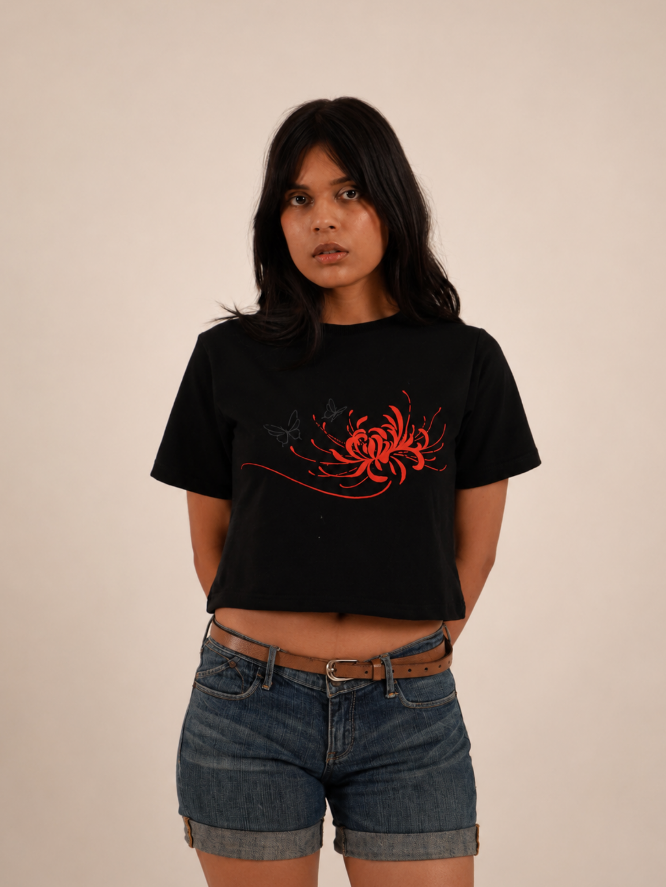 Female model wearing premium black crop top featuring crimson spider lily chest print
