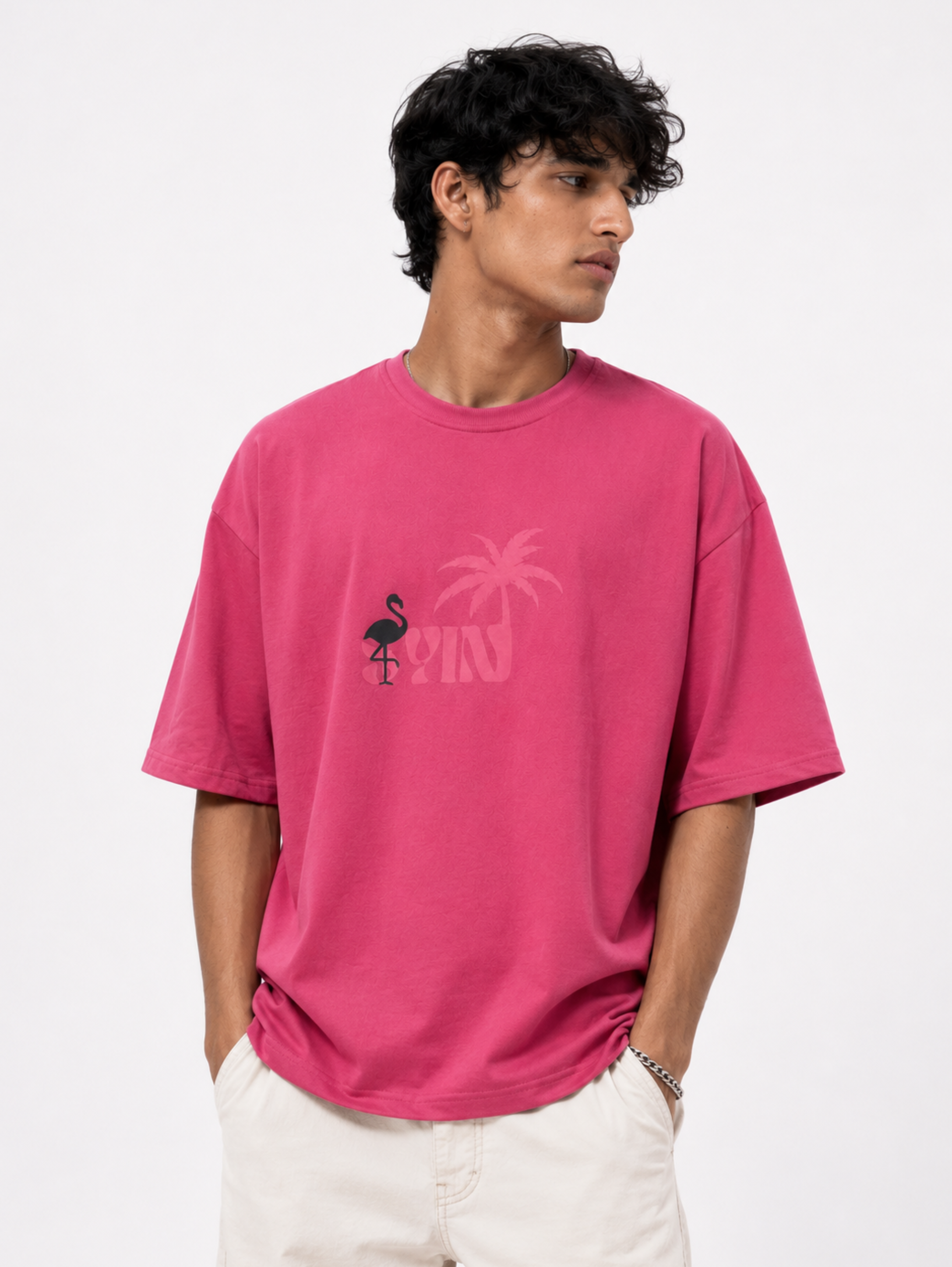 Male model wearing Emerge in Pink premium oversized pink t-shirt with minimalist tropical branding

