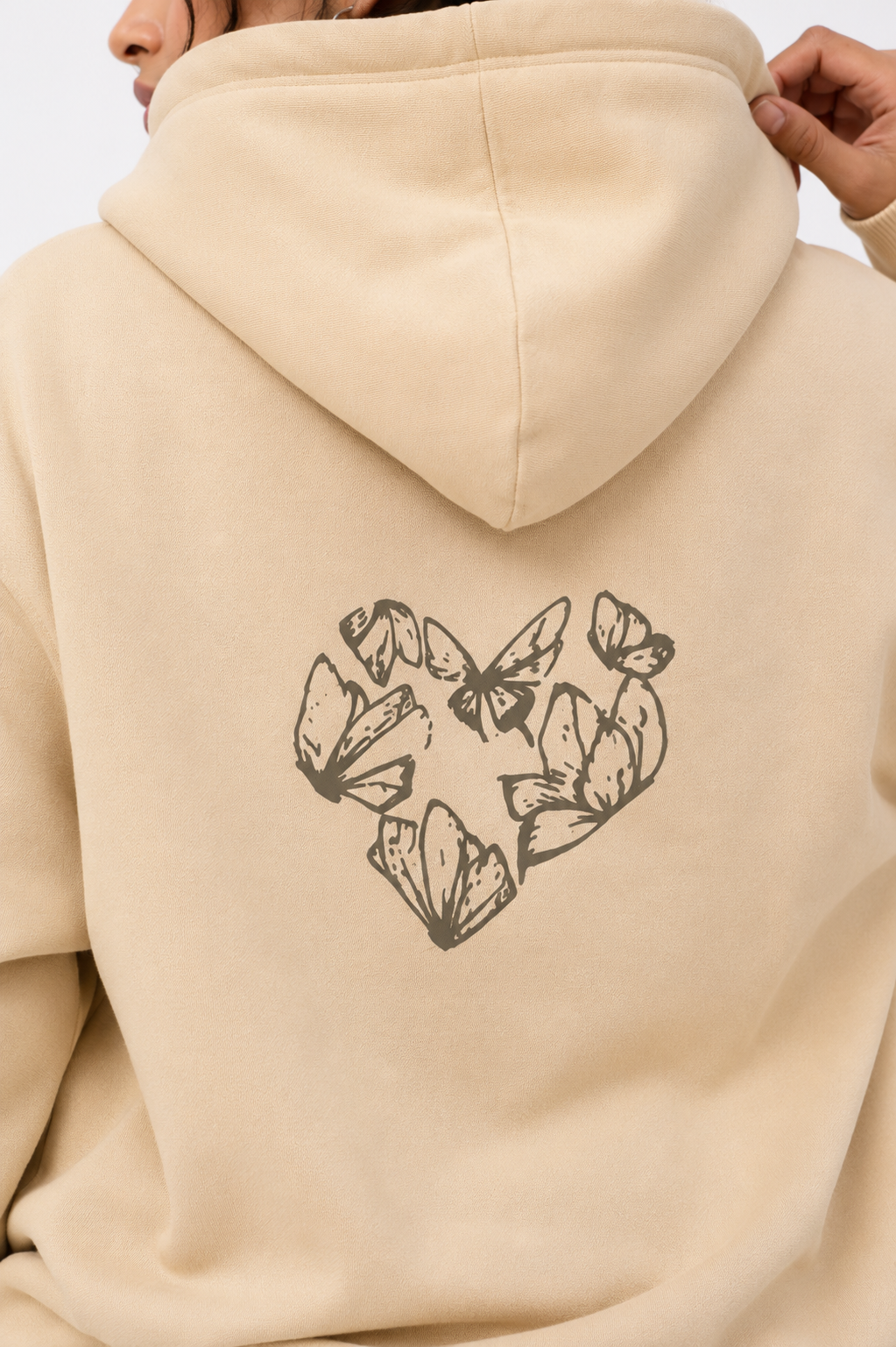 Close-up of the Karmic Bloom oversized sand beige hoodie showcasing the butterfly heart artwork printed on the back.
