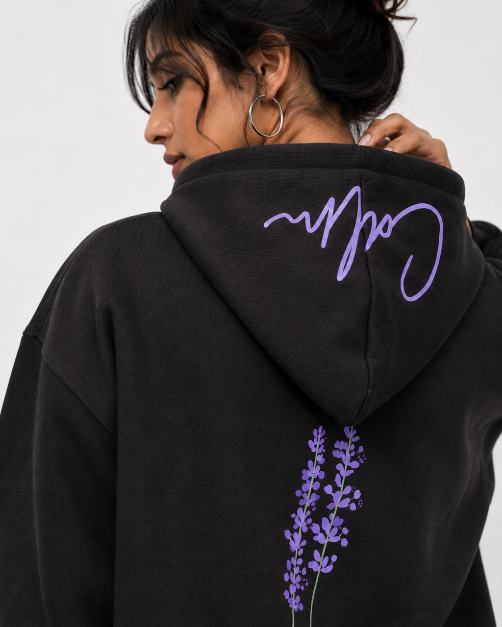 Close-up of the Midnight Lavender oversized hoodie showcasing the lavender botanical artwork and signature script on the hood.