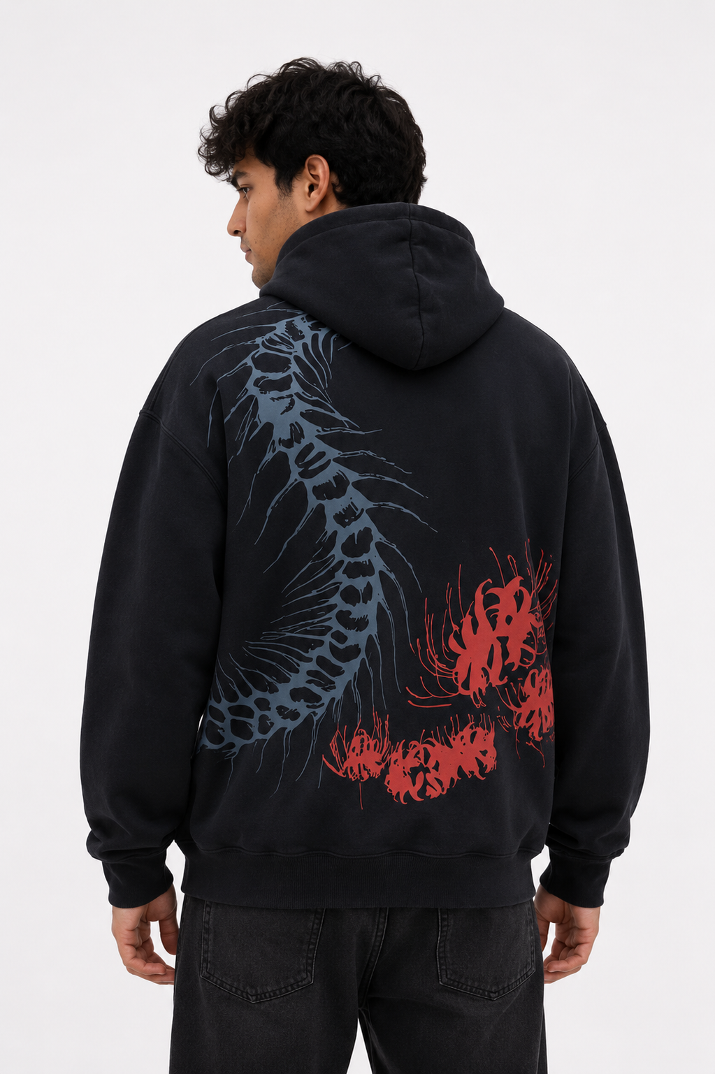 Male model wearing the Silken Spine oversized black hoodie featuring the large spine graphic and red floral illustration across the back.
