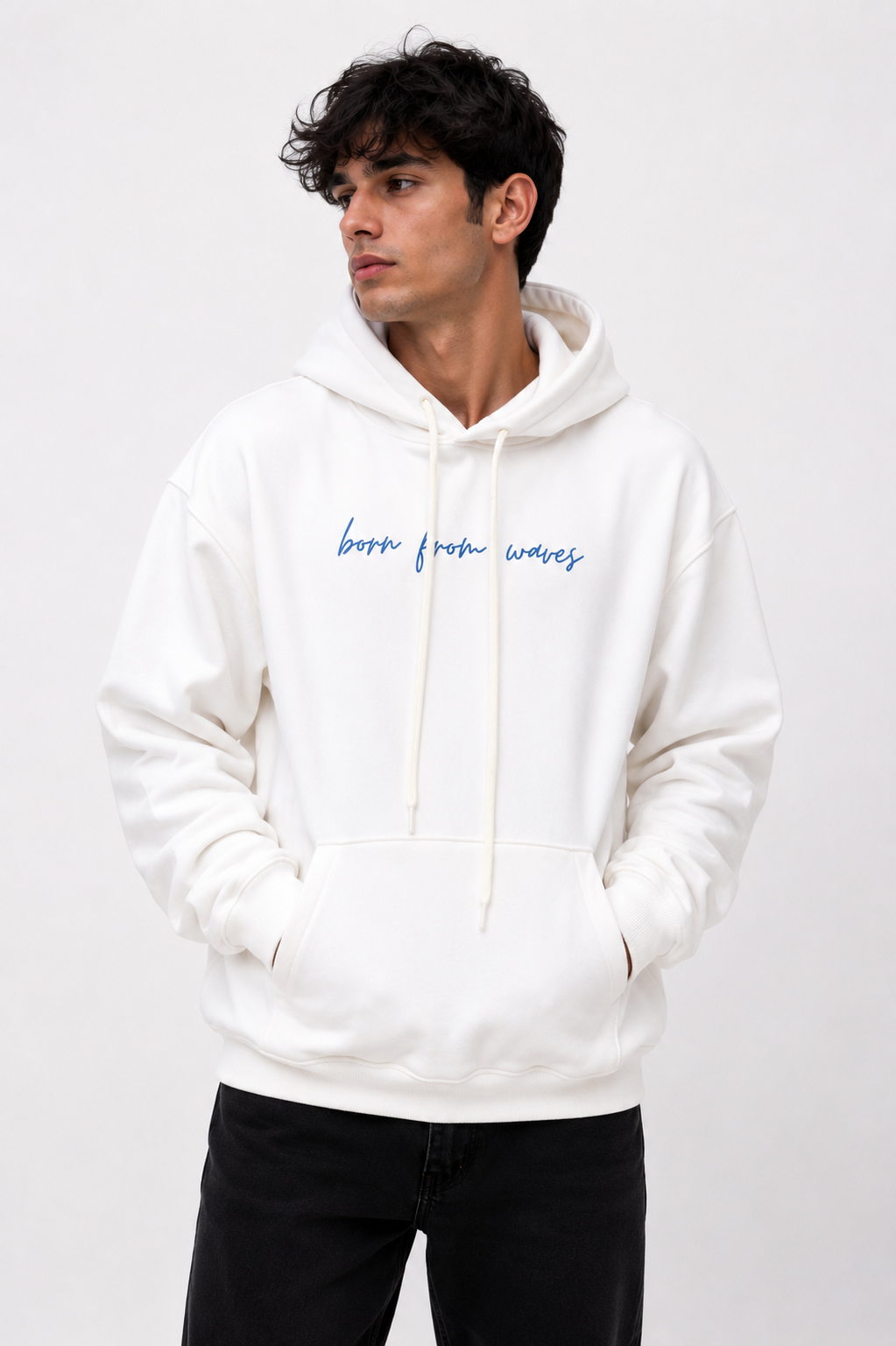 Front view of the Soul Born oversized white hoodie worn by a male model featuring the "Born From Waves" graphic.
