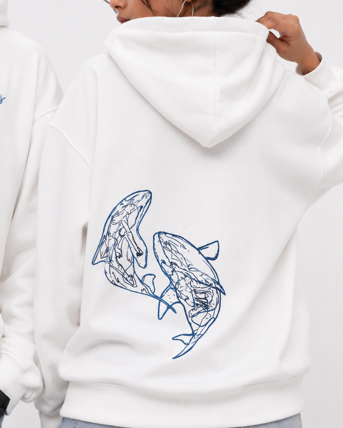 Close-up of the Soul Born oversized white hoodie featuring the blue twin whale artwork on the back.
