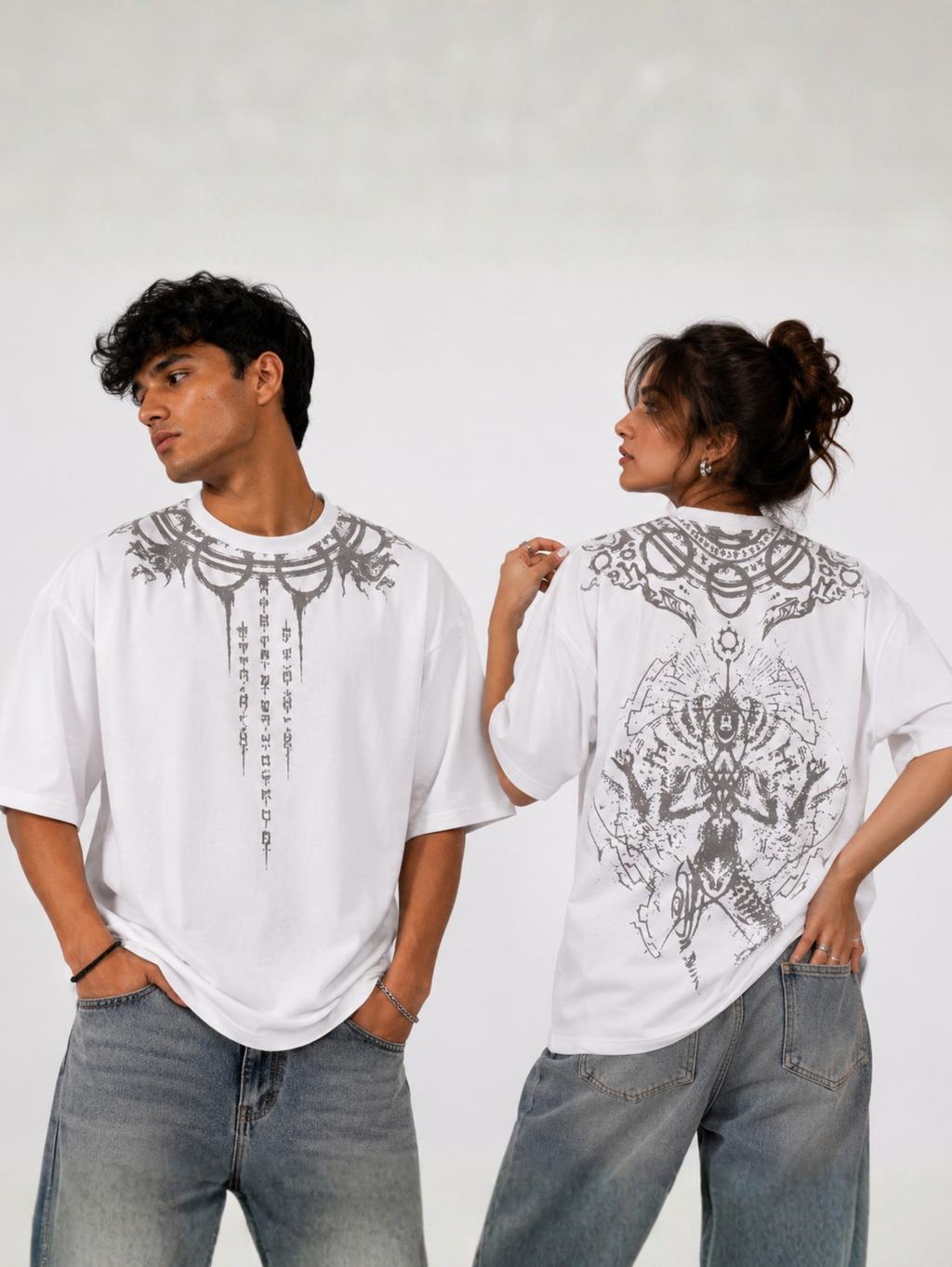 Male and female models wearing the Vishnu Ascendent premium oversized white T-shirt by Syin&Syrah showcasing the celestial neckline artwork on the front and intricate Vishnu-inspired back graphic in a premium studio photoshoot.