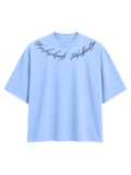 Winged Curse oversized sky blue cotton T-shirt by SYIN & SYRAH featuring gothic typography across the neckline and premium heavyweight streetwear construction.