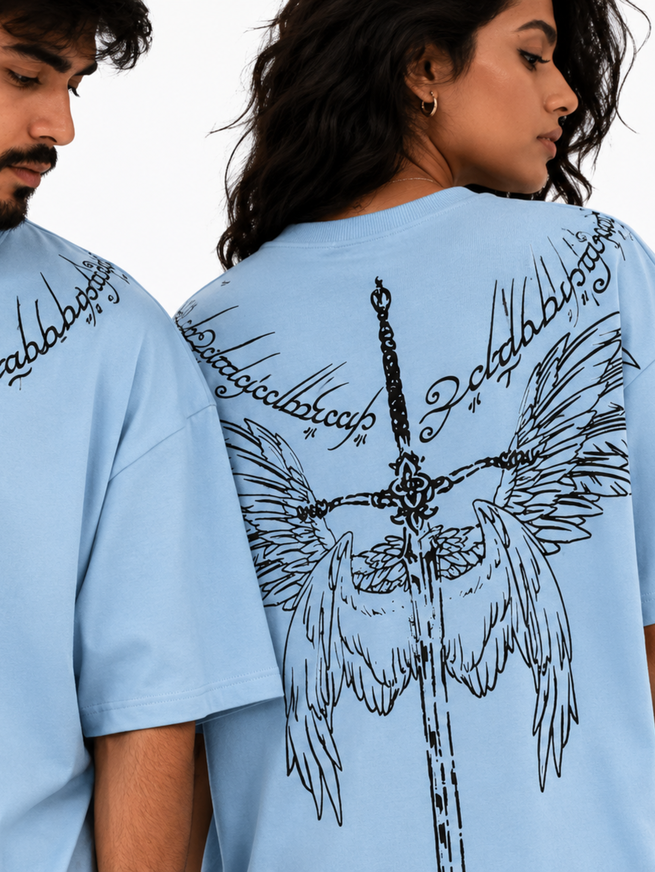 Close-up of the Winged Curse oversized sky blue T-shirt by SYIN & SYRAH showcasing the gothic neckline print on the front and winged sword graphic on the back with premium cotton fabric and high-quality screen print