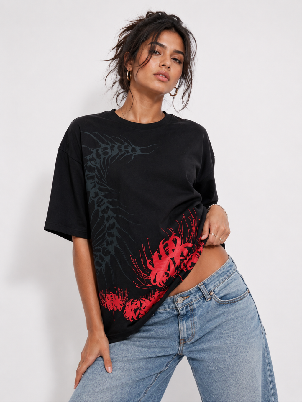 Female model wearing the Silken Spine premium oversized black streetwear T-shirt by SYIN & SYRAH with abstract spine graphic and vibrant red spider lily artwork.