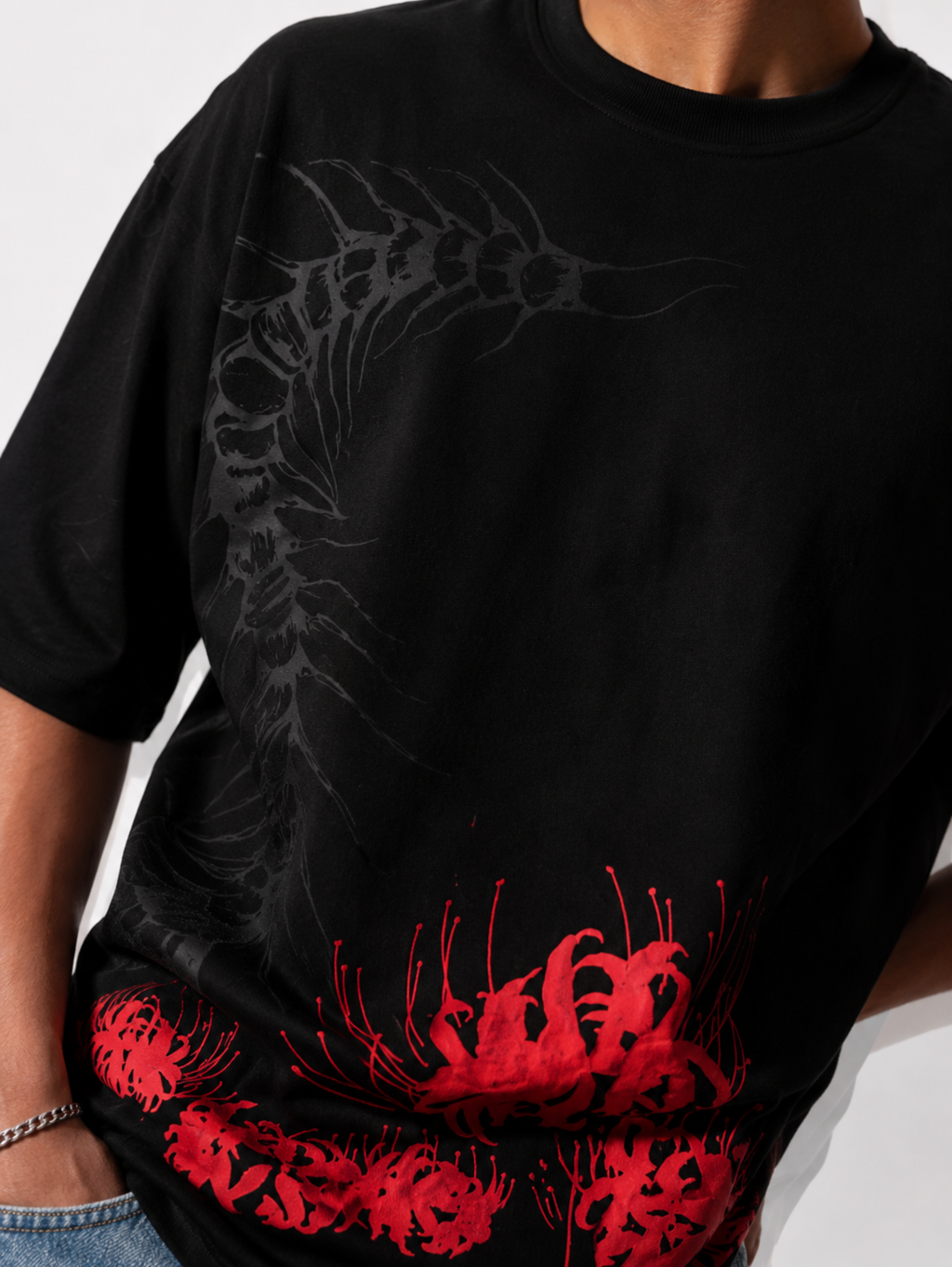 Close-up of the Silken Spine premium oversized black cotton T-shirt by SYIN & SYRAH showcasing the abstract spine artwork, vibrant red spider lily print, heavyweight fabric, and premium print quality.